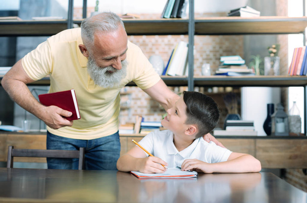 Mindful grandparent helping kid with home assignment - Foto, immagini