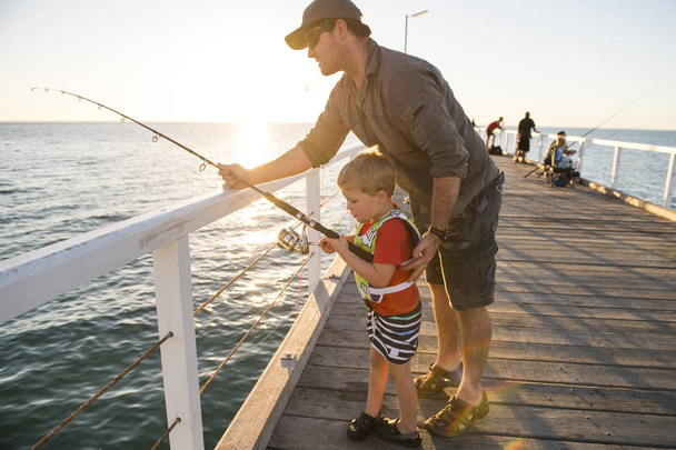 père enseignant petit fils à être un pêcheur, pêchant ensemble sur le quai de la mer en appréciant et apprenant à utiliser la canne à poisson
 - Photo, image