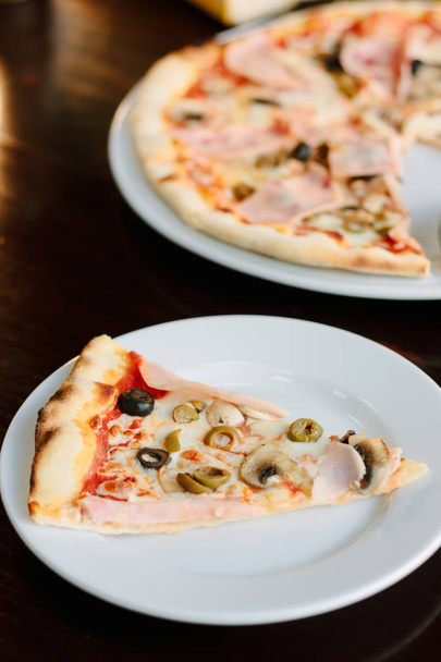 Pilz-Pizza-Scheibe auf weißem Keramikteller über dem Tisch - Foto, Bild