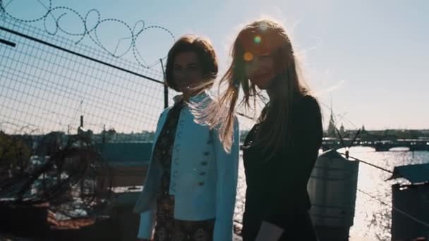 Two lovely young girls on rooftop with scenic city river view - Footage, Video
