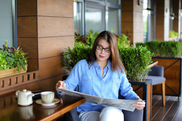 Encantadora mujer leyendo el periódico en el restaurante y tomando té
 - Foto, Imagen