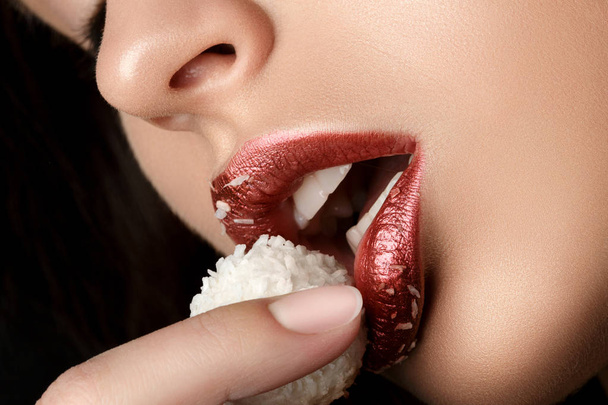 Close up view of female lips eating coconut candy - Foto, imagen