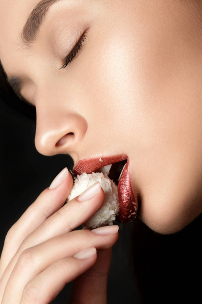 Vista de cerca de los labios femeninos comiendo caramelos de coco
 - Foto, imagen
