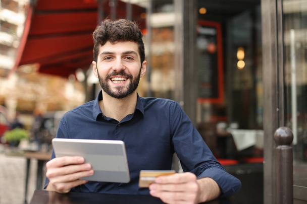 Uomo felice shopping online con carta e tablet al caffè di strada wi
 - Foto, immagini