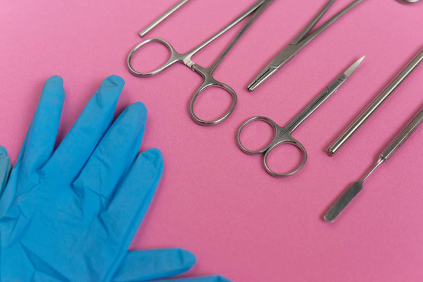 on a pink background is a dental instrument and medical gloves - Foto, Imagen