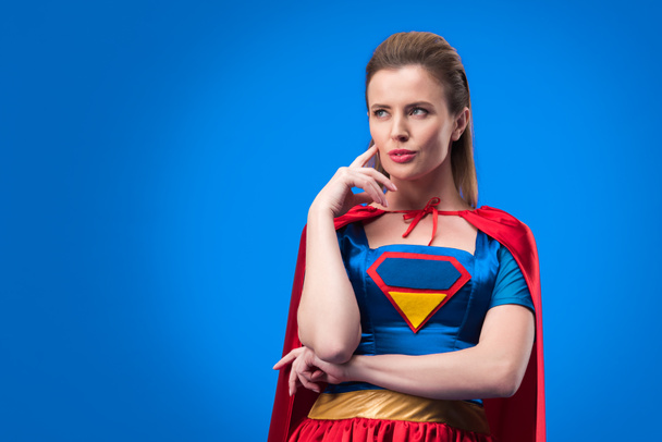 retrato de mujer pensativa en traje de superhéroe mirando hacia otro lado aislado en azul
 - Foto, Imagen