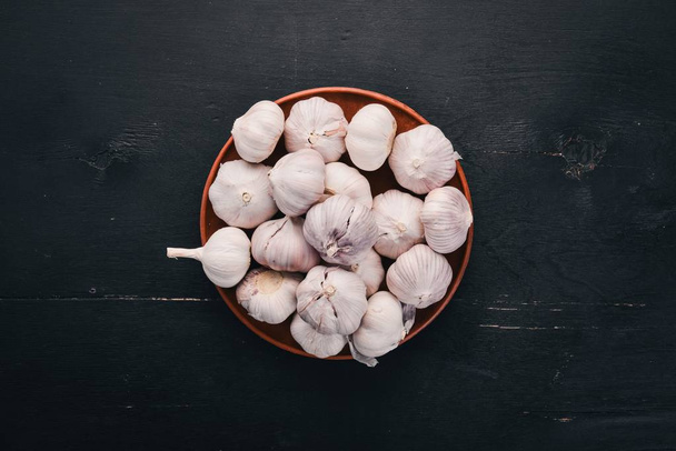 Garlic on a plate. Fresh garlic on a wooden background. Top view. Copy space. - Fotó, kép