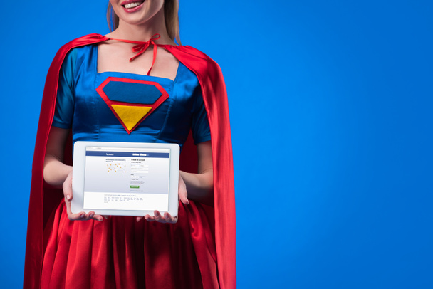 vista parziale della donna in costume da supereroe mostrando tablet isolato su blu
 - Foto, immagini