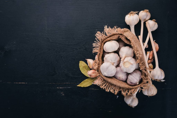 Garlic in a sack of old cloth. Fresh garlic on a wooden background. Top view. Free space for text. - 写真・画像