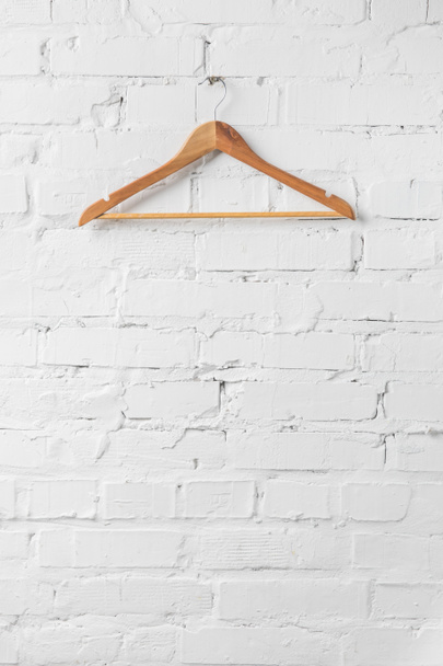 one brown wooden hanger on white wall - 写真・画像