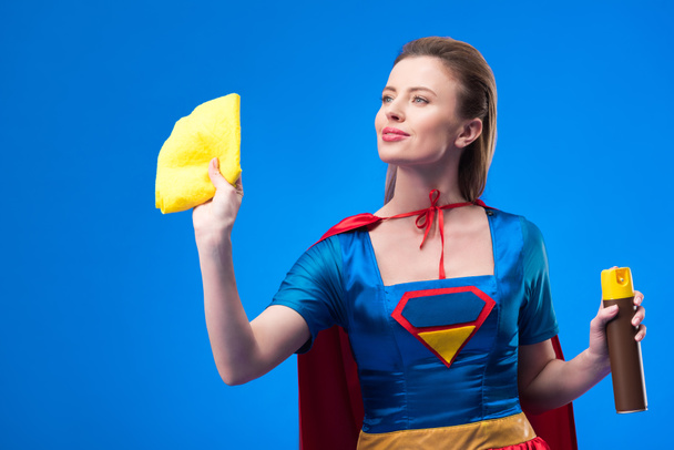 portrait of beautiful superwoman with rag and detergent for cleaning isolated on blue - Foto, Imagem