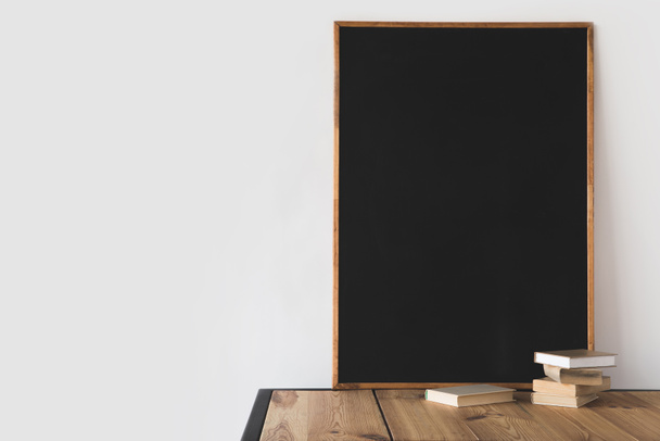 books and big blackboard on wooden table on white  - Zdjęcie, obraz