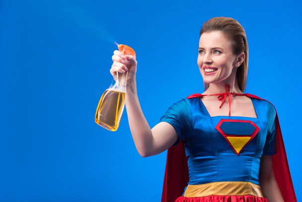 portrait of cheerful superwoman with detergent in hand isolated on blue - Foto, afbeelding