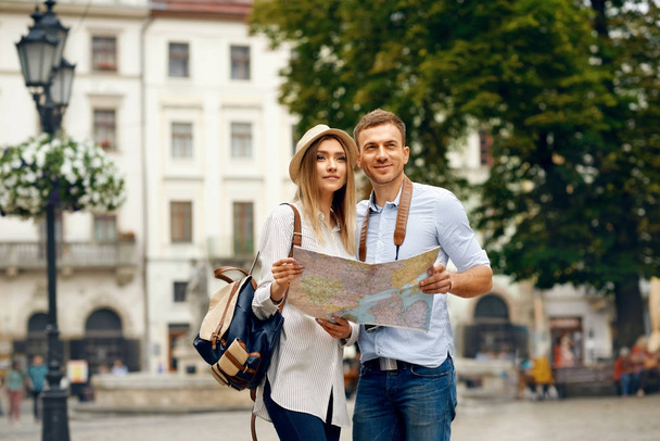 Toeristische paar met kaart lopen op straat. - Foto, afbeelding