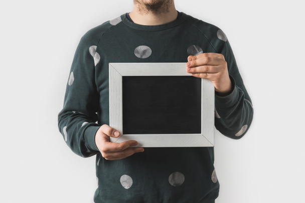 abgeschnittenes Bild eines Mannes mit leerer schwarzer Tafel auf weißem Hintergrund - Foto, Bild
