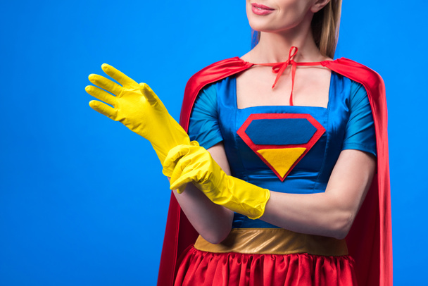 cropped shot of woman in superhero costume wearing rubber gloves isolated on blue - Foto, Imagem