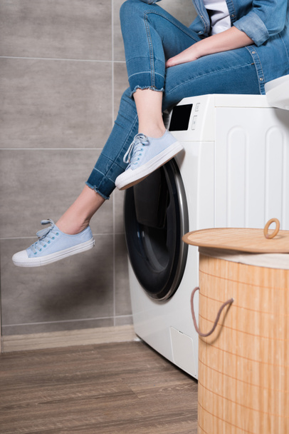 частковий вид домогосподарки, що сидить на пральній машині вдома
 - Фото, зображення