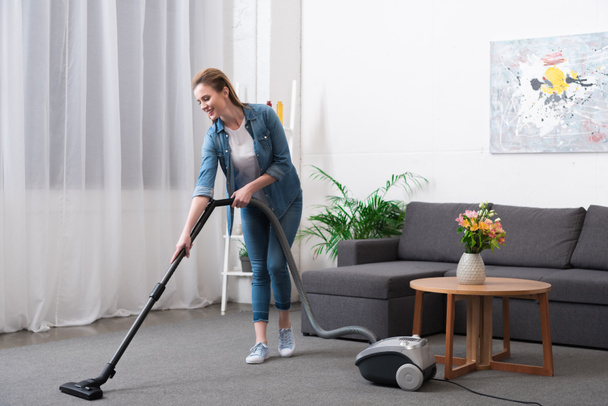 attractive woman with vacuum cleaner cleaning room at home - Foto, Bild