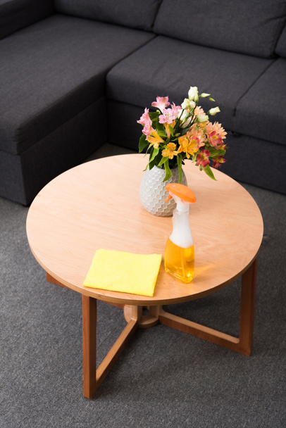 vista ravvicinata di fiori in vaso, detersivo e straccio sul tavolino in legno
 - Foto, immagini