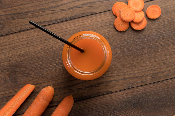 Karottensaft in einem Glas auf einem hölzernen Hintergrund, Draufsicht. Konzept der gesunden Ernährung, Rohkost-Ernährung, Ernährung. - Foto, Bild