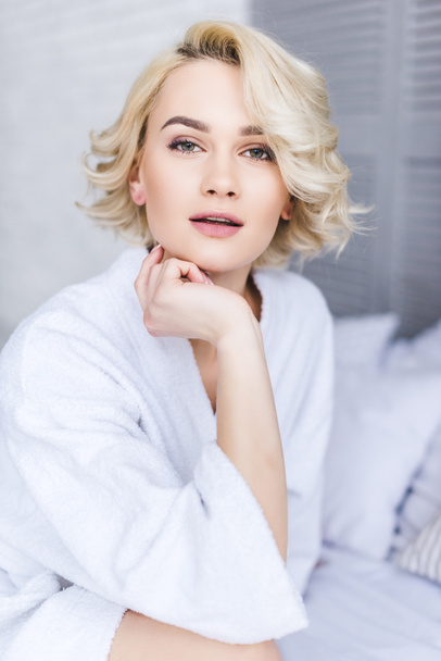 portrait of beautiful young blonde woman in bathrobe looking at camera - Фото, изображение