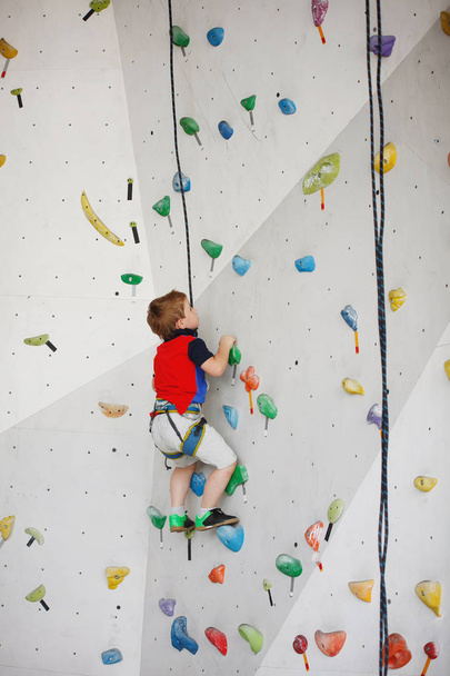 Niño escalando en una pared alta
 - Foto, Imagen