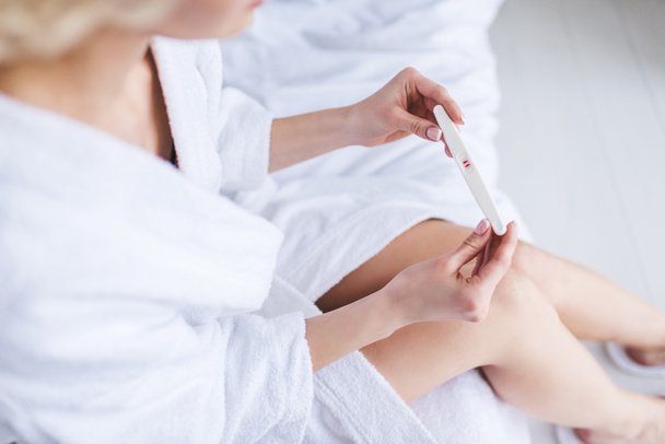 cropped shot of young woman in bathrobe holding positive pregnancy test  - Foto, immagini