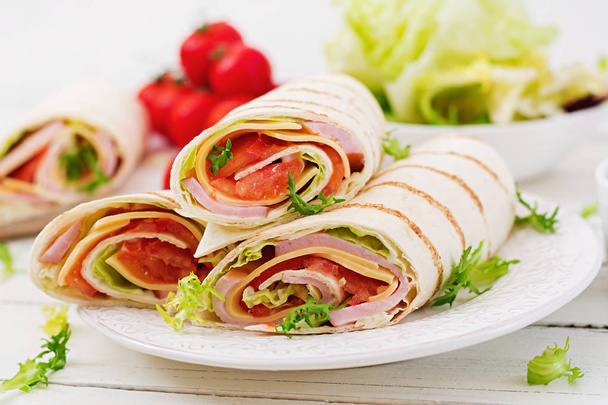 Tortilla wrap with ham, cheese and tomatoes on a white wooden background - Photo, Image