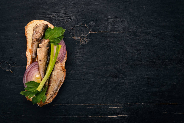 Sandwich con espadines, cebolla y perejil, sobre fondo de madera. Vista superior. Copiar espacio
. - Foto, Imagen