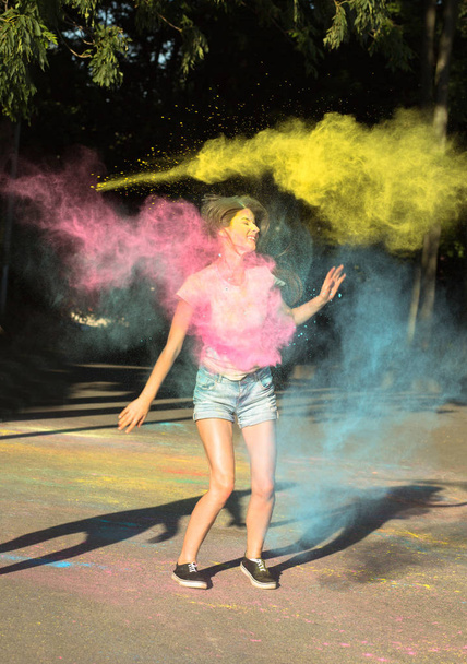Awesome young woman jumping with exploding pink, blue and yellow - Foto, Imagem