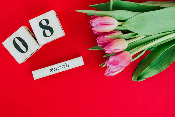 8. März fröhliches Frauentag-Konzept. mit Holzblock-Kalender und rosa Tulpen auf rotem Hintergrund - Foto, Bild