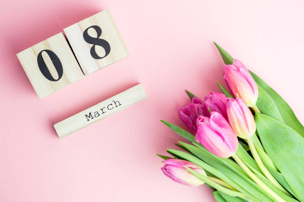 8 maart Happy Women's Day concept. Met houten blok kalender en roze tulpen op roze achtergrond - Foto, afbeelding