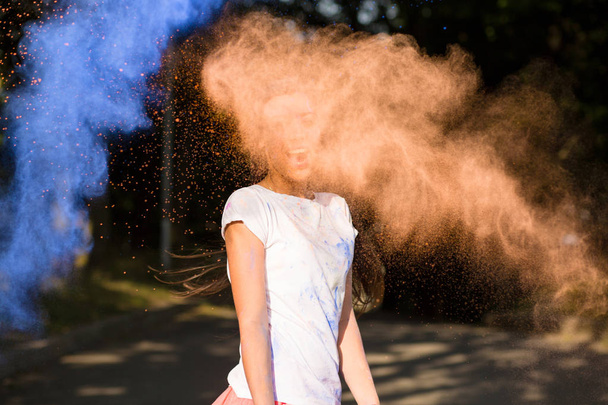 Expressive young asian woman having fun with Holi paint explodin - Foto, Imagen
