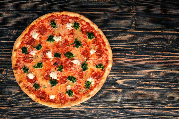 Neapolitan Pizza. Spinach, gorgonzola cheese, sausage salami. On a wooden background. Top view. - Foto, Imagem