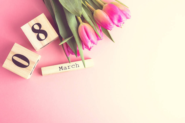 8. März fröhliches Frauentag-Konzept. mit Holzblock-Kalender und rosa Tulpen auf rosa Hintergrund - Foto, Bild