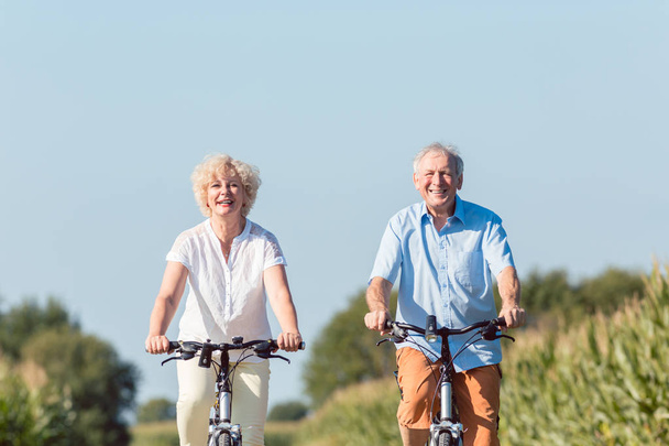 Senior couple looking forward with confidence while riding bicyc - Photo, Image