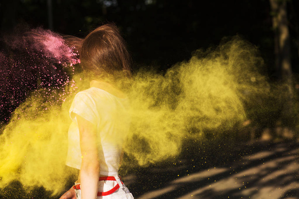 Brunette woman with hair in wind posing with yellow powder Holi  - Foto, Imagem
