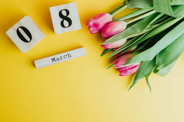 8 March Happy Women's Day concept. With wooden block calendar and pink tulips on yellow background. Copy space - Photo, Image