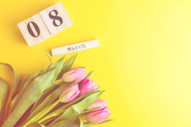 8 березня щасливі жіночий день концепції. З дерев'яних блоків календар і рожеві тюльпани на жовтому фоні. Копія простір - Фото, зображення