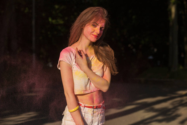 Cool brunette woman posing covered with yellow and pink Holi paint - Foto, Bild