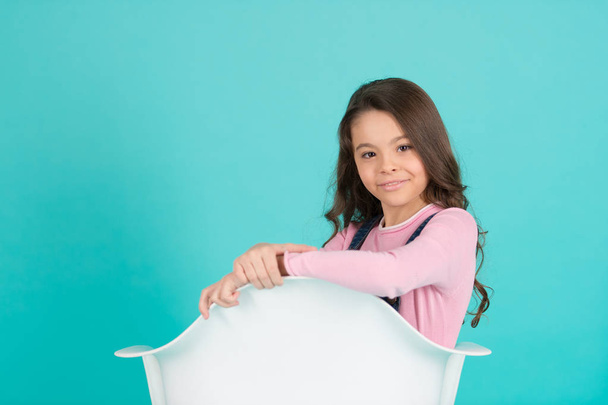 Kid pose in white armchair on blue background - Фото, изображение