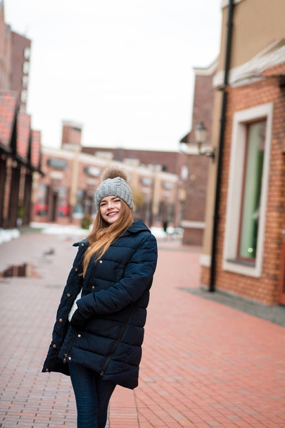 Felice giovane donna che indossa cappotto invernale nero e cappello a maglia posi
 - Foto, immagini