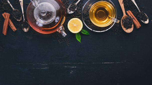 Tea in a glass cup with spices and herbs. On a black wooden background. Top view. Copy space. - Foto, afbeelding