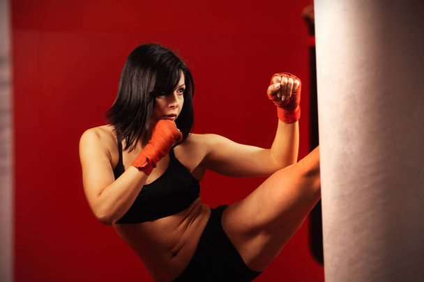 Attractive young woman working out a gym. Close up image of middle eastern female in sports clothing. Fit body of beautiful, healthy and sporty girl. Boxing training woman with punching bag in gym. - Photo, Image