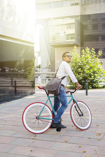 A young stylish man posing next to his bicycle. - 写真・画像