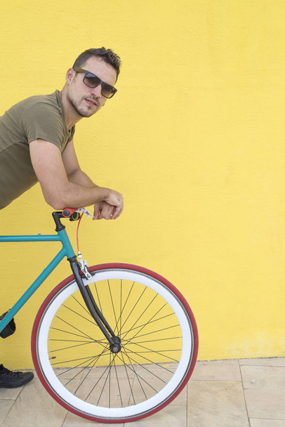 Man posing with his fixed gear bicycle wearing a hat and sunglasses - Foto, imagen