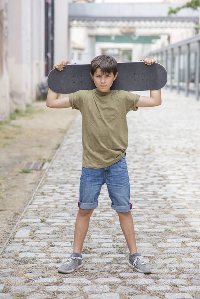Close-up of a teenage boy carrying skateboard and smiling - Foto, Imagem