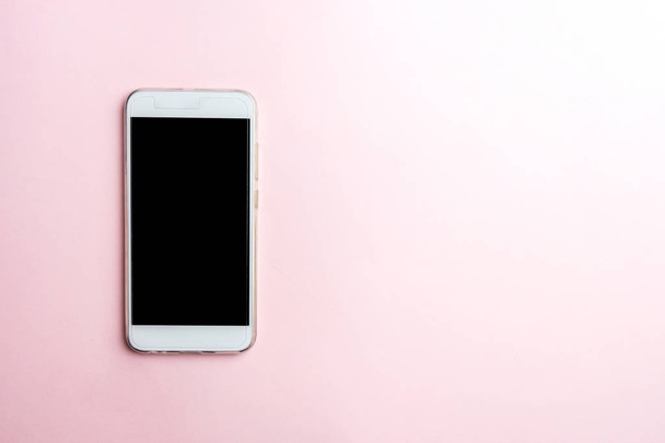 White mobile phone on pink background. Copy space, top view - Photo, Image