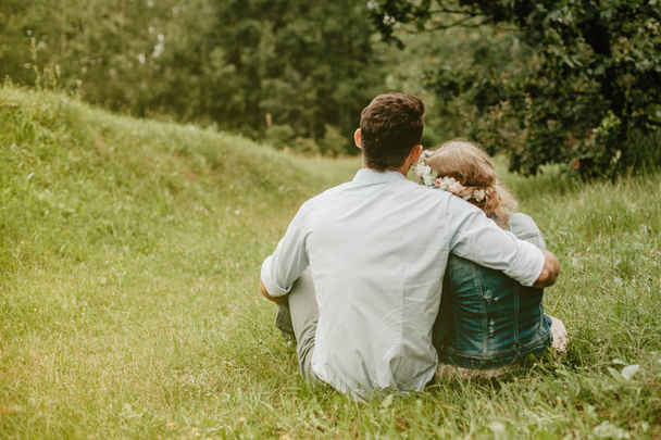 草の上に座っていて、ロマンチックな夜のカップル。愛の概念 - 写真・画像