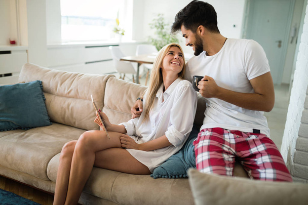 Young attractive couple spending time together at home using tablet - Zdjęcie, obraz